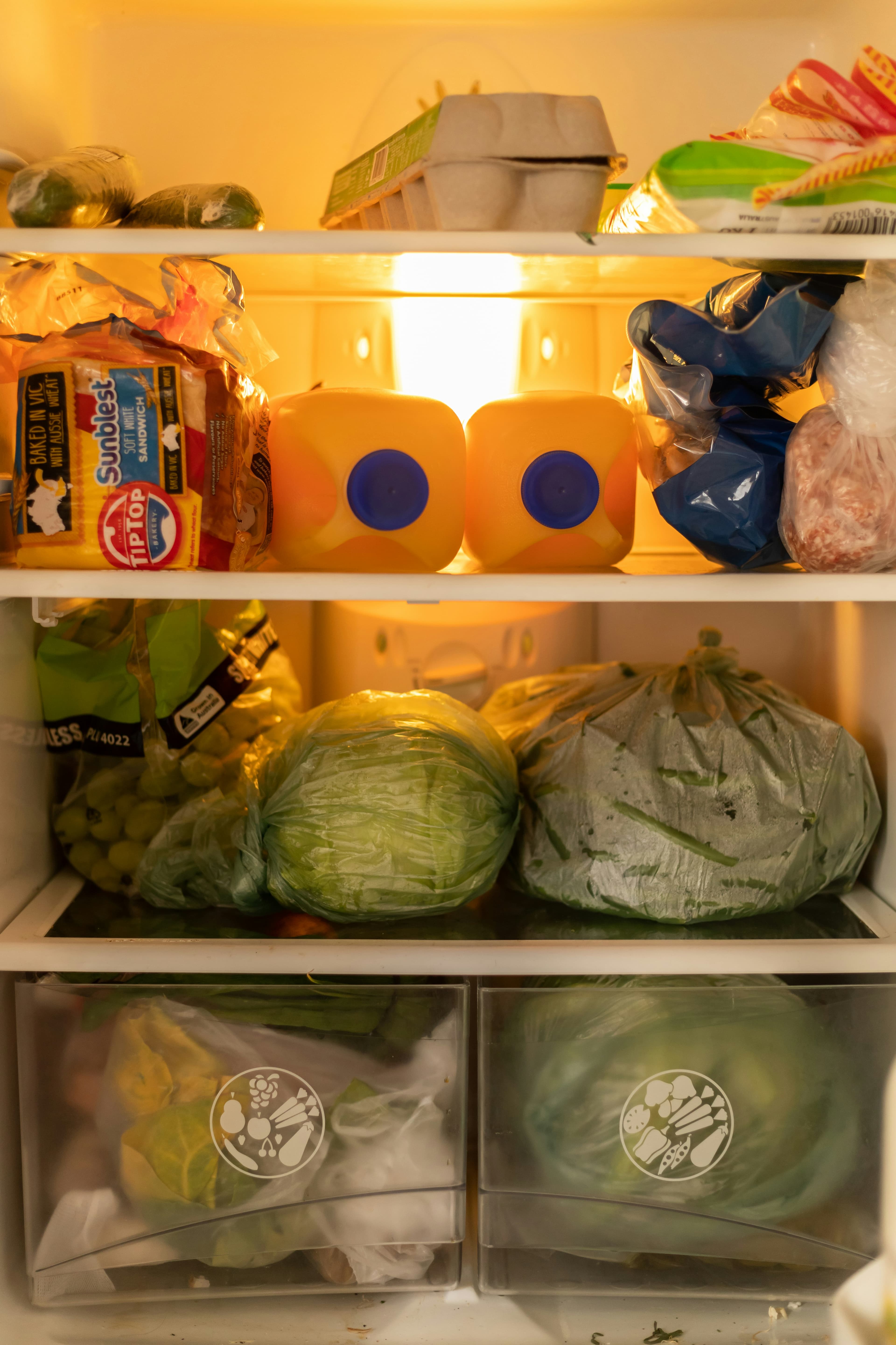 Open refrigerator stocked with fresh vegetables and ingredients